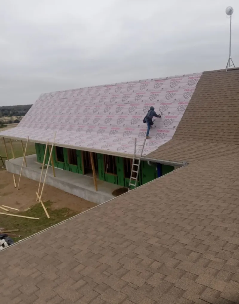 Worker preparing underlayment for a metal roof installation in Fountain